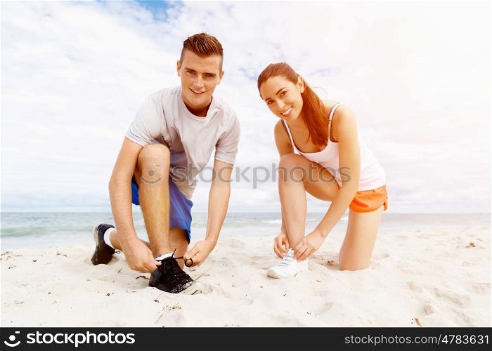 Runners lace their shoes and prepare to jogging. Couple of runners lace their shoes and prepare to jogging