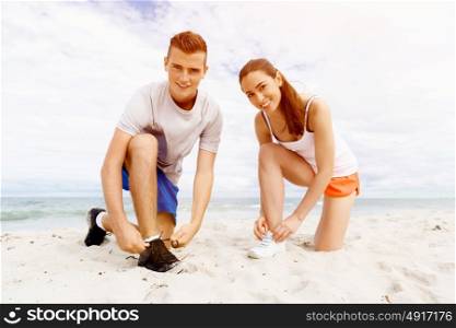 Runners lace their shoes and prepare to jogging. Couple of runners lace their shoes and prepare to jogging
