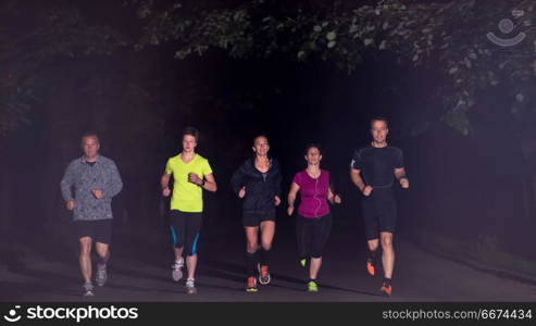 runners team on the night training. group of healthy people jogging in city park, runners team at night training