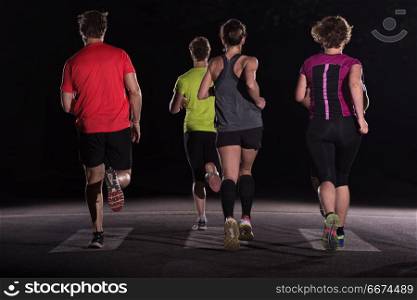 runners team on the night training. group of healthy people jogging in city park, runners team at night training