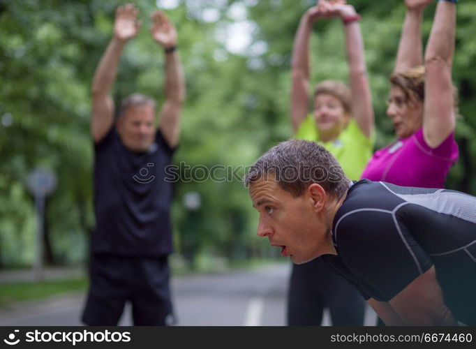 runners team warming up and stretching before morning training. healthy runners team warming up and stretching in city park before morning training