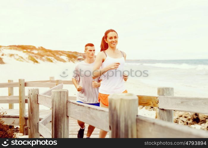 Runners. Young couple running on beach. Runners. Young couple running on beach together