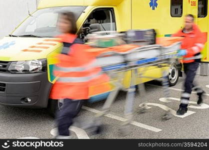 Running blurry paramedics team with stretcher and ambulance car