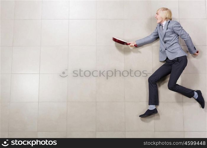 Running businessman. Funny image of young running businessman with pan in hand