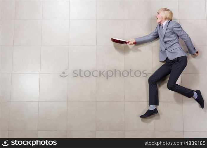 Running businessman. Funny image of young running businessman with pan in hand