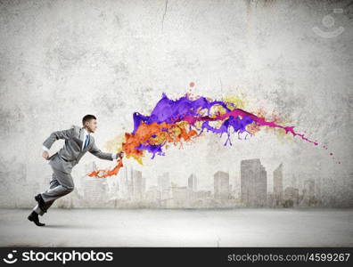 Running businessman. Young running businessman with colorful splashes in hand