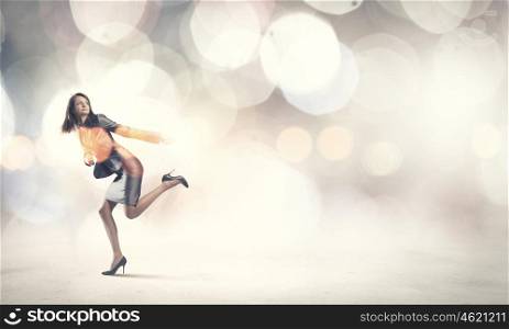 Running businesswoman. Young businesswoman in suit running against bokeh background