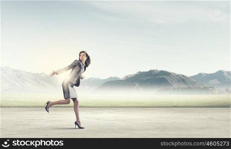 Running businesswoman. Young businesswoman in suit running on road
