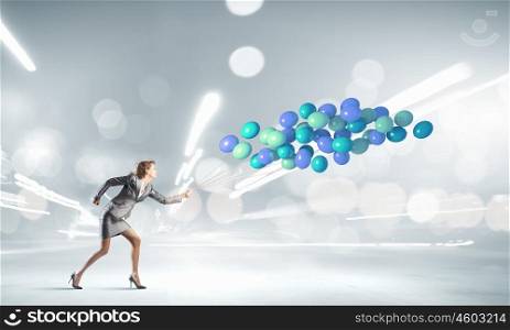 Running businesswoman. Young businesswoman running with bunch of colorful balloons