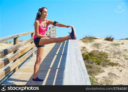 running girl stretching in a beach track with headphores