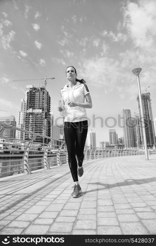 Running in city park. Woman runner outside jogging at morning with Dubai urban scene in background