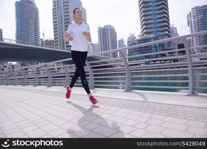 Running in city park. Woman runner outside jogging at morning with Dubai urban scene in background