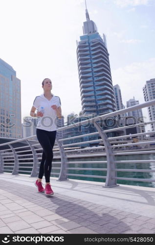 Running in city park. Woman runner outside jogging at morning with Dubai urban scene in background