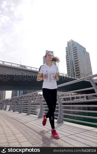 Running in city park. Woman runner outside jogging at morning with Dubai urban scene in background