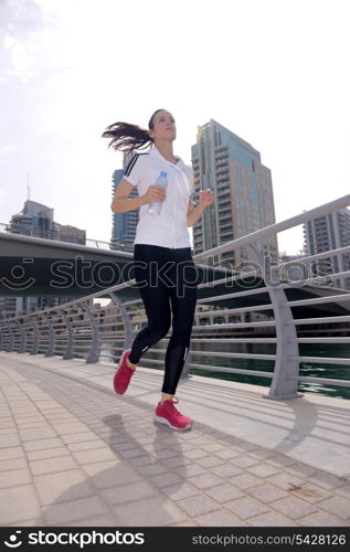 Running in city park. Woman runner outside jogging at morning with Dubai urban scene in background