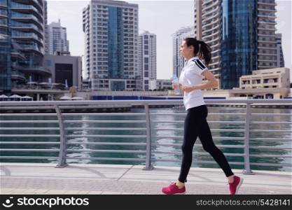 Running in city park. Woman runner outside jogging at morning with Dubai urban scene in background