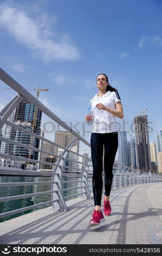 Running in city park. Woman runner outside jogging at morning with Dubai urban scene in background