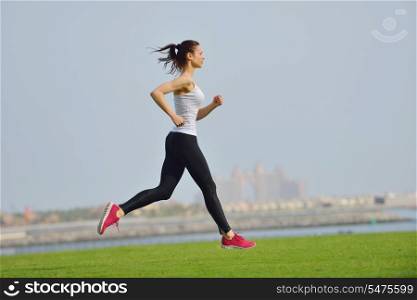Running in city park. Woman runner outside jogging at morning with Dubai urban scene in background