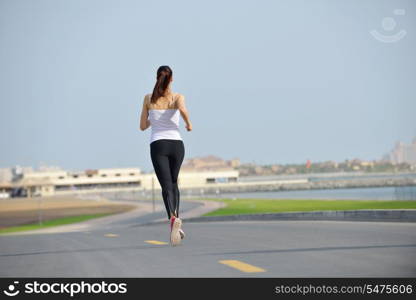 Running in city park. Woman runner outside jogging at morning with Dubai urban scene in background