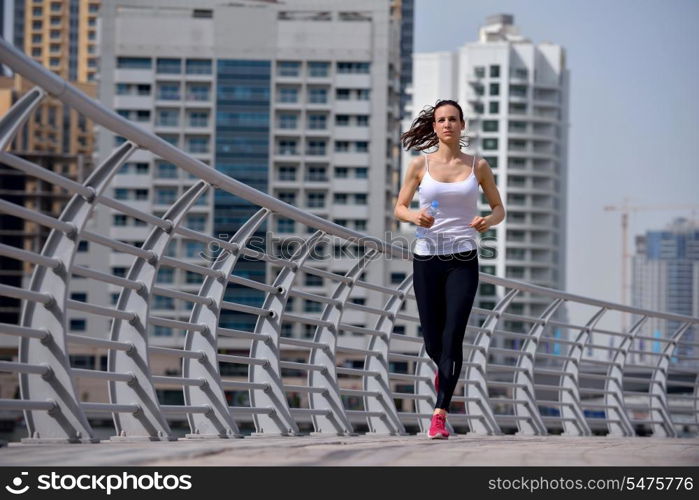 Running in city park. Woman runner outside jogging at morning with Dubai urban scene in background