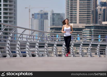 Running in city park. Woman runner outside jogging at morning with Dubai urban scene in background