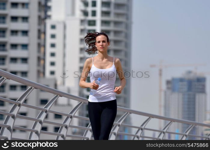 Running in city park. Woman runner outside jogging at morning with Dubai urban scene in background