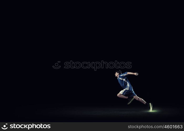 Running man in blue sport wear on black background. At full speed