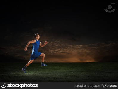 Running man in blue sport wear on black background. At full speed