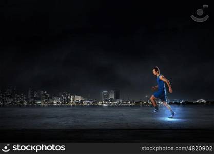 Running man in blue sport wear on black background. At full speed