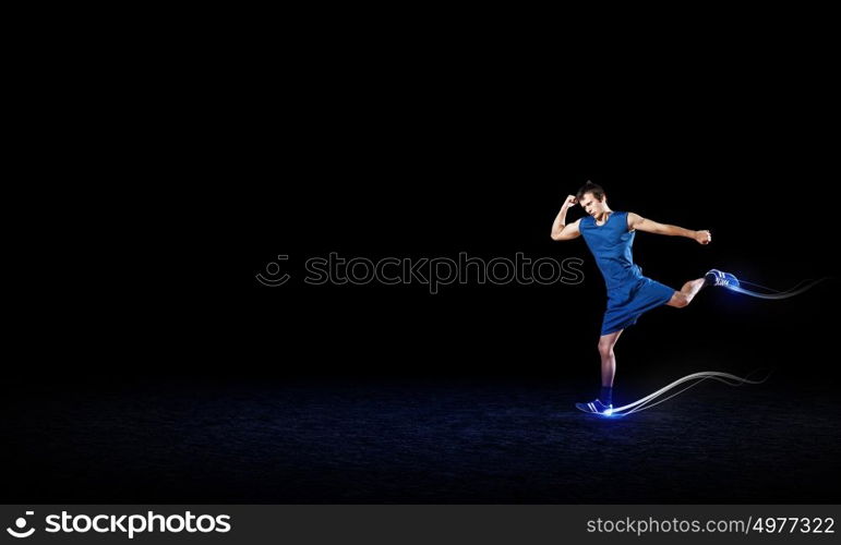 Running man in blue sport wear on black background. At full speed