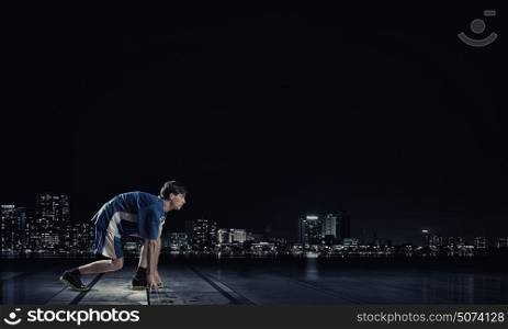 Running man in blue sport wear on black background. At full speed