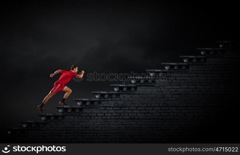 Running man in red sport wear on black background. At full speed