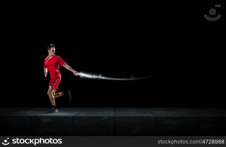 Running man in red sport wear on black background. At full speed
