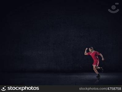 Running man in red sport wear on black background. At full speed