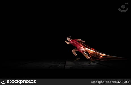 Running man in red sport wear on black background. At full speed