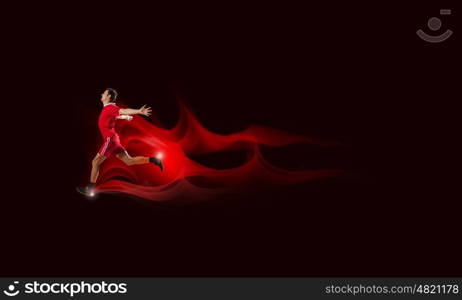 Running man in red sport wear on black background. At full speed