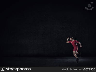 Running man in red sport wear on black background. At full speed