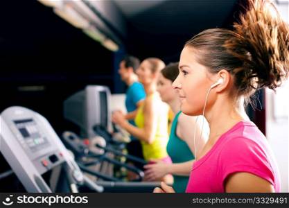 Running on treadmill in gym - group of women and men exercising to gain more fitness