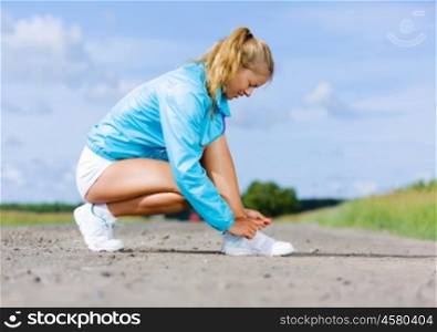 Running outdoor. Young healthy girl tie shoelaces of sneakers