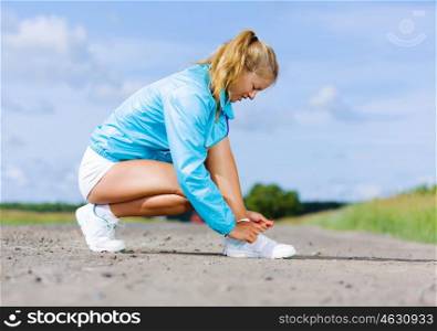 Running outdoor. Young healthy girl tie shoelaces of sneakers