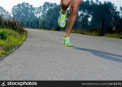 Running sport shoes outdoors in action on country road. Male shoes on young man training. Slight motion blur, focus on back running shoe.