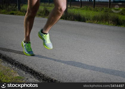 Running sport shoes outdoors in action on country road. Male shoes on young man training. Slight motion blur, focus on back running shoe.