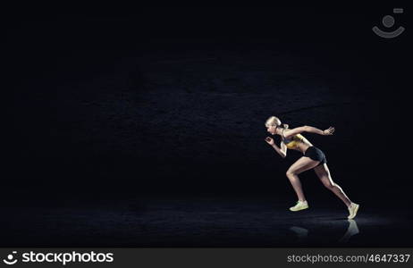 Running woman in sport wear on black background. At full speed