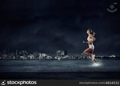 Running woman in sport wear on black background. At full speed