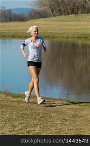 Running woman outdoor sport by river bank sunny day