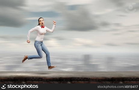 Running woman. Young funny pretty woman in jeans running in a hurry