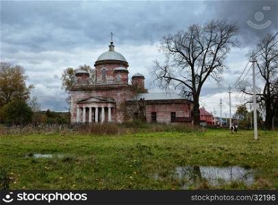 Rural autumn landscape with old abandoned church and overcast sky