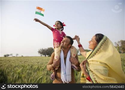 Rural family in the field with girl holding Indian flag
