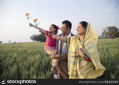 Rural family standing in the field holding Indian flag