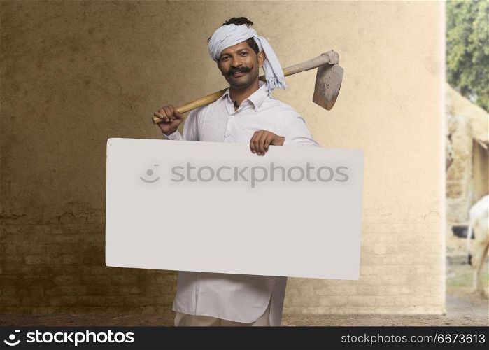 Rural farmer carrying hoe on his shoulder and holding placard